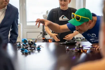 Teilnehmer eines DroneMasters-Meetups begutachten FPV-Renndrohnen am Tisch