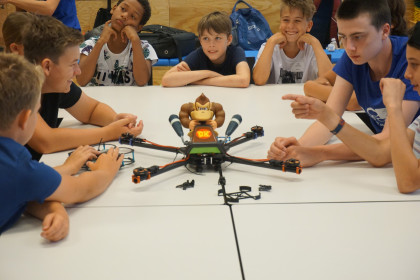 Jugendliche der Junior Academy arbeiten am Tisch an einem großen Hexacopter