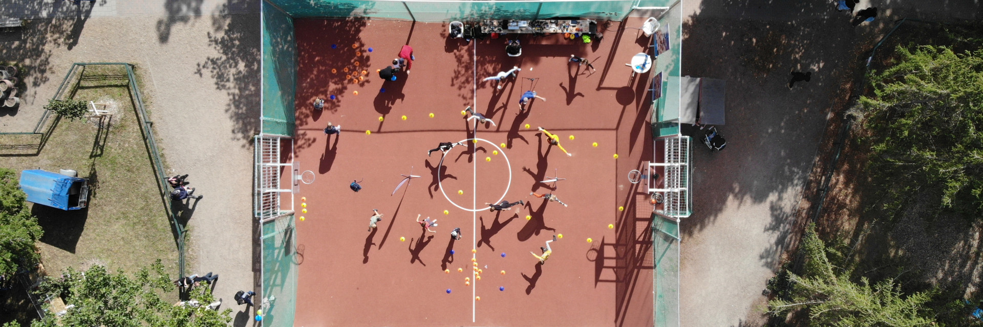 Luftaufnahme: Kursgruppe auf dem eingezäunten Sportplatz der Schule Grünheide