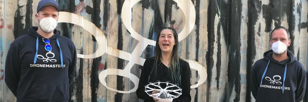 Drei Teammitglieder mit dem Modell-Volocopter vor dem DroneMasters-Container