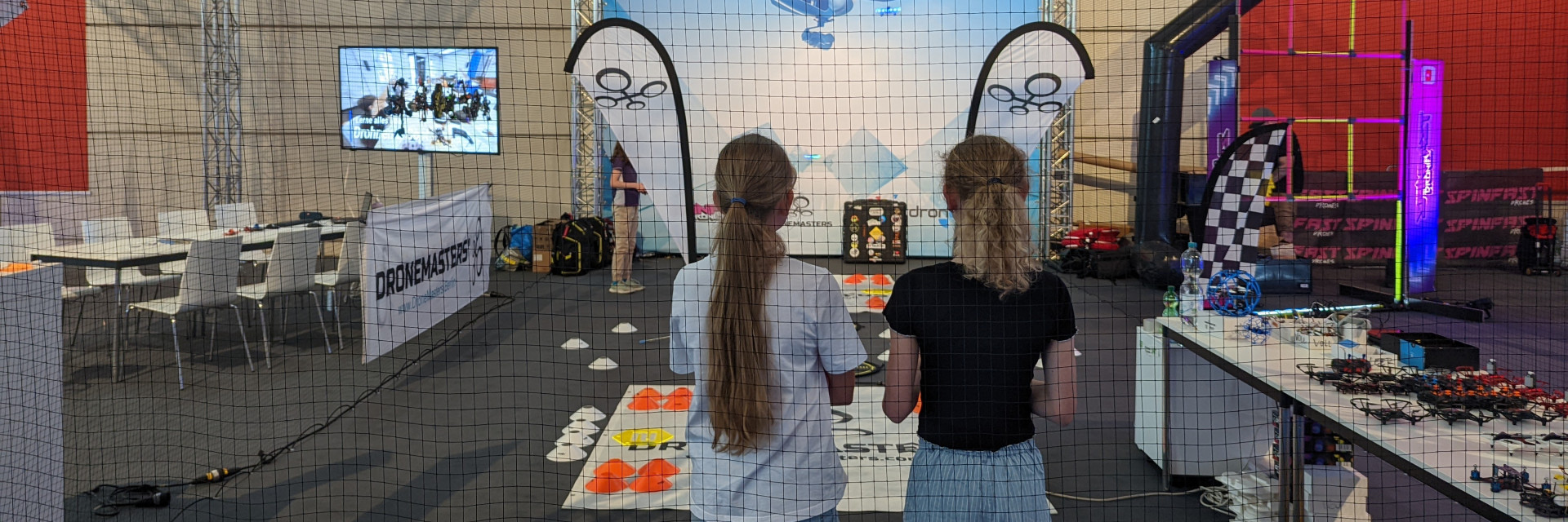 Zwei Mädchen bestaunen den Messestand der DroneMasters Academy